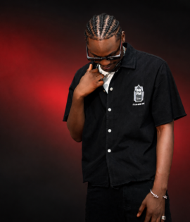 Front view of a model wearing the BLAQFAM PREMIUM black collared shirt against a dark red backdrop